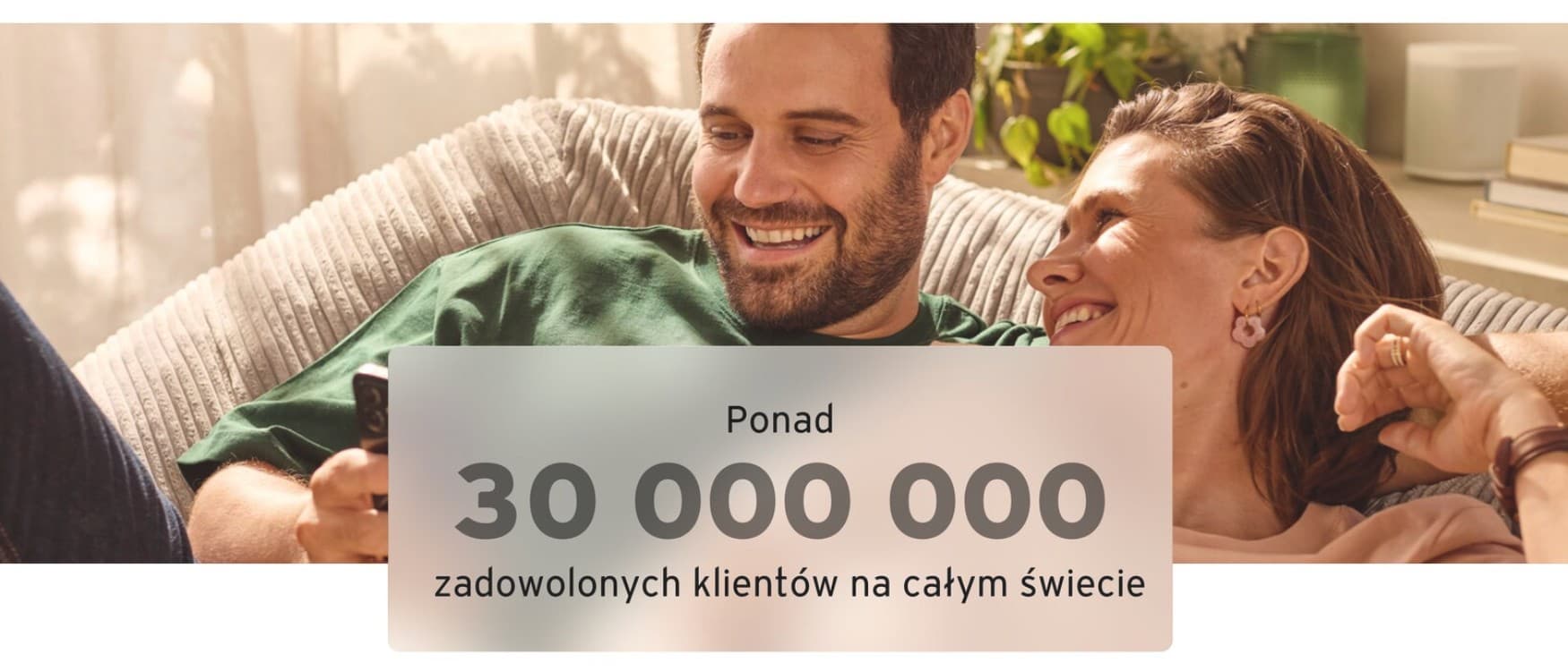 Para siedząca wygodnie w środku, uśmiechająca się i patrząca na telefon